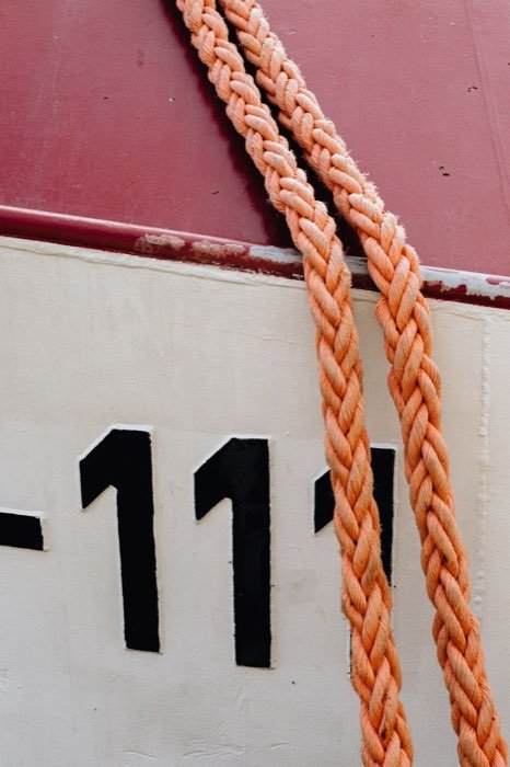 Braided mooring ropes running down the painted hull of a vessel alongside.